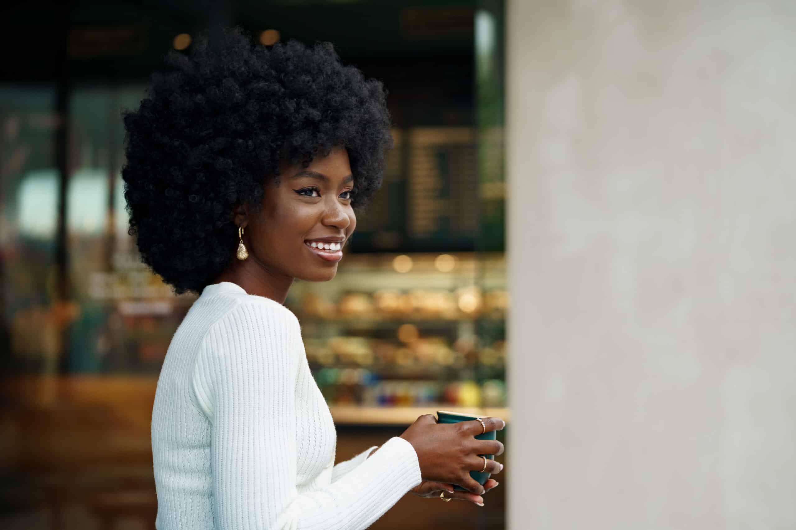 Portrait of young african woman with afro hairstyle smiling in urban background